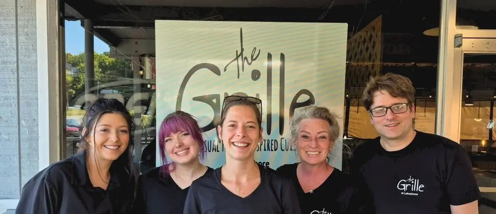 The Grille at Lakeshore front-of-house team in front of the restaurant sign